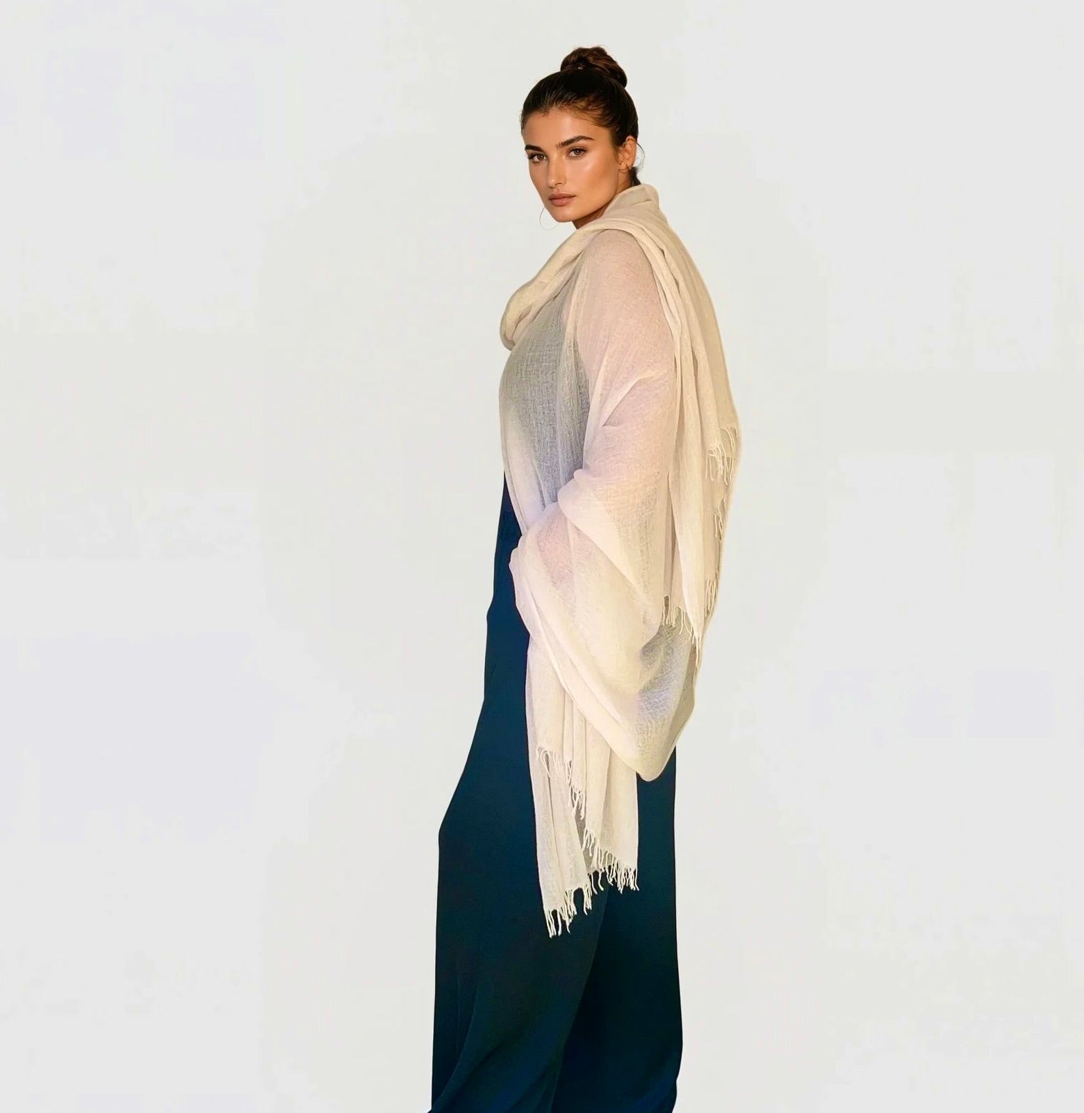Woman wearing a soft pink extra large cashmere shawl with a white background.