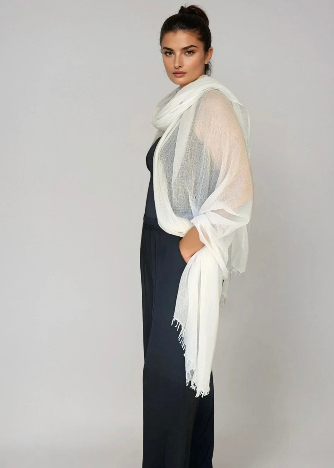 A woman wearing a white oversized pure cashmere shawl draped over her shoulders.