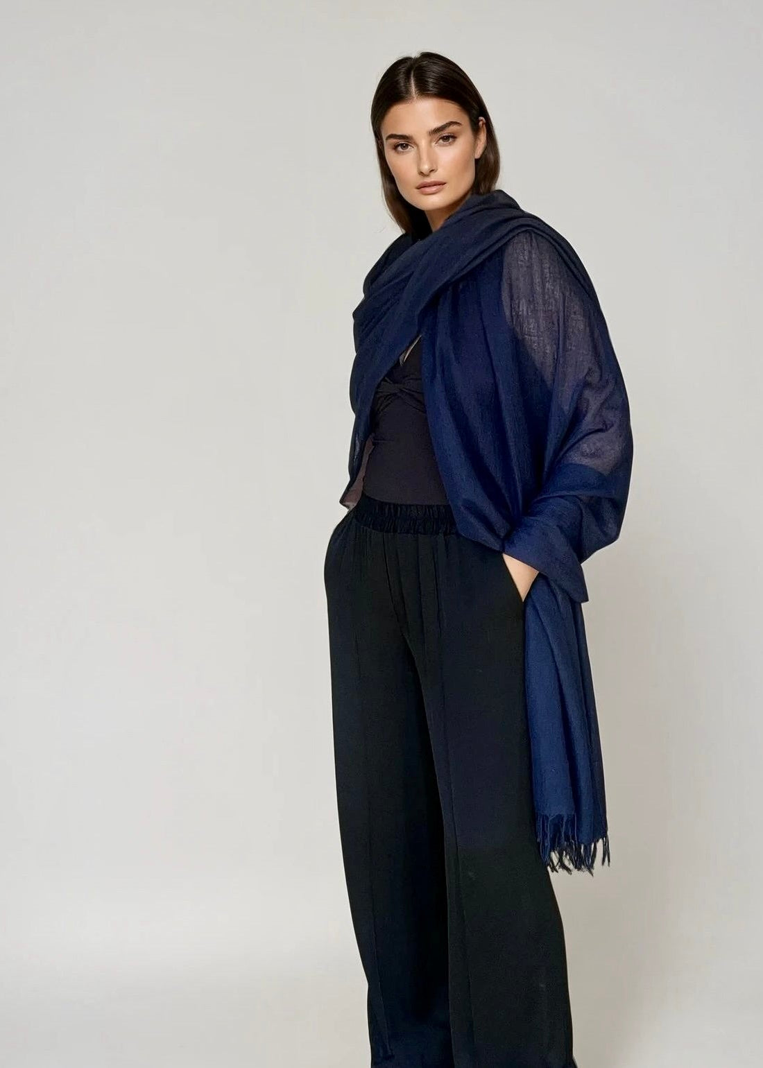 Woman wearing a navy blue extra large cashmere shawl on a city street.