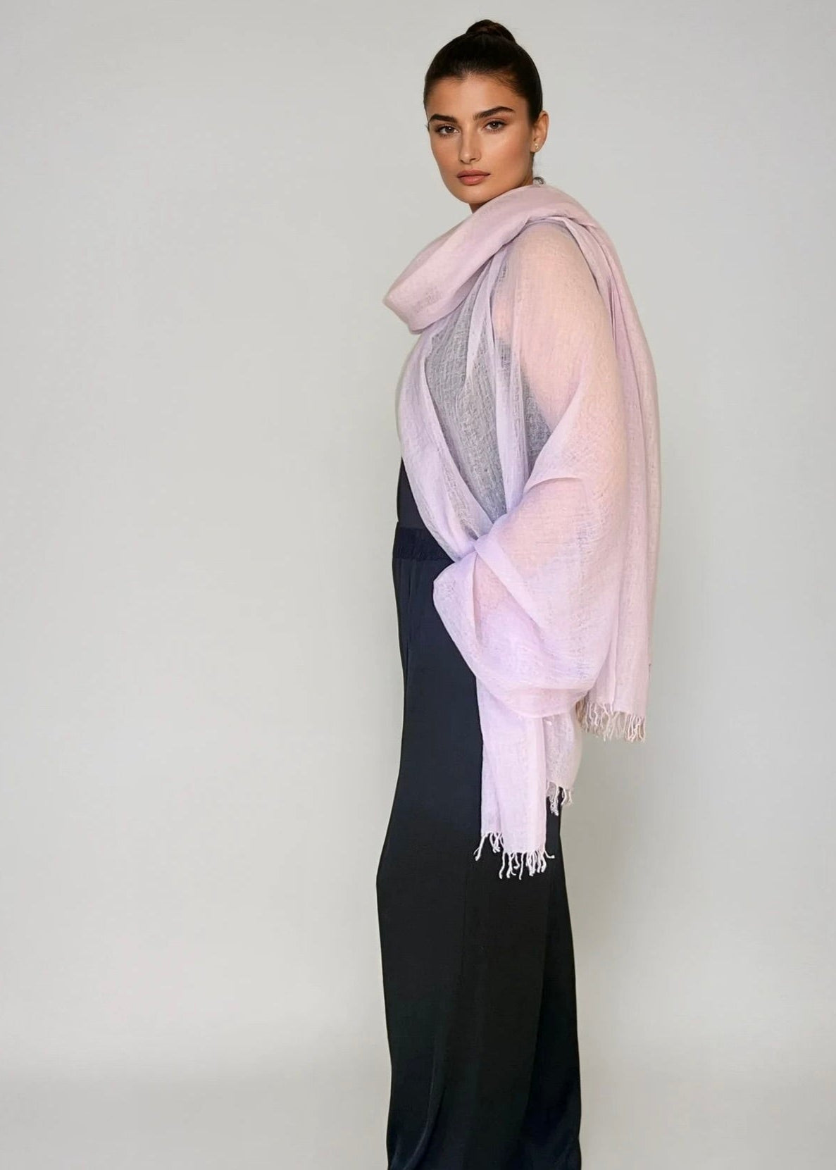 Woman wearing a extra large cashmere lavender shawl in a studio.