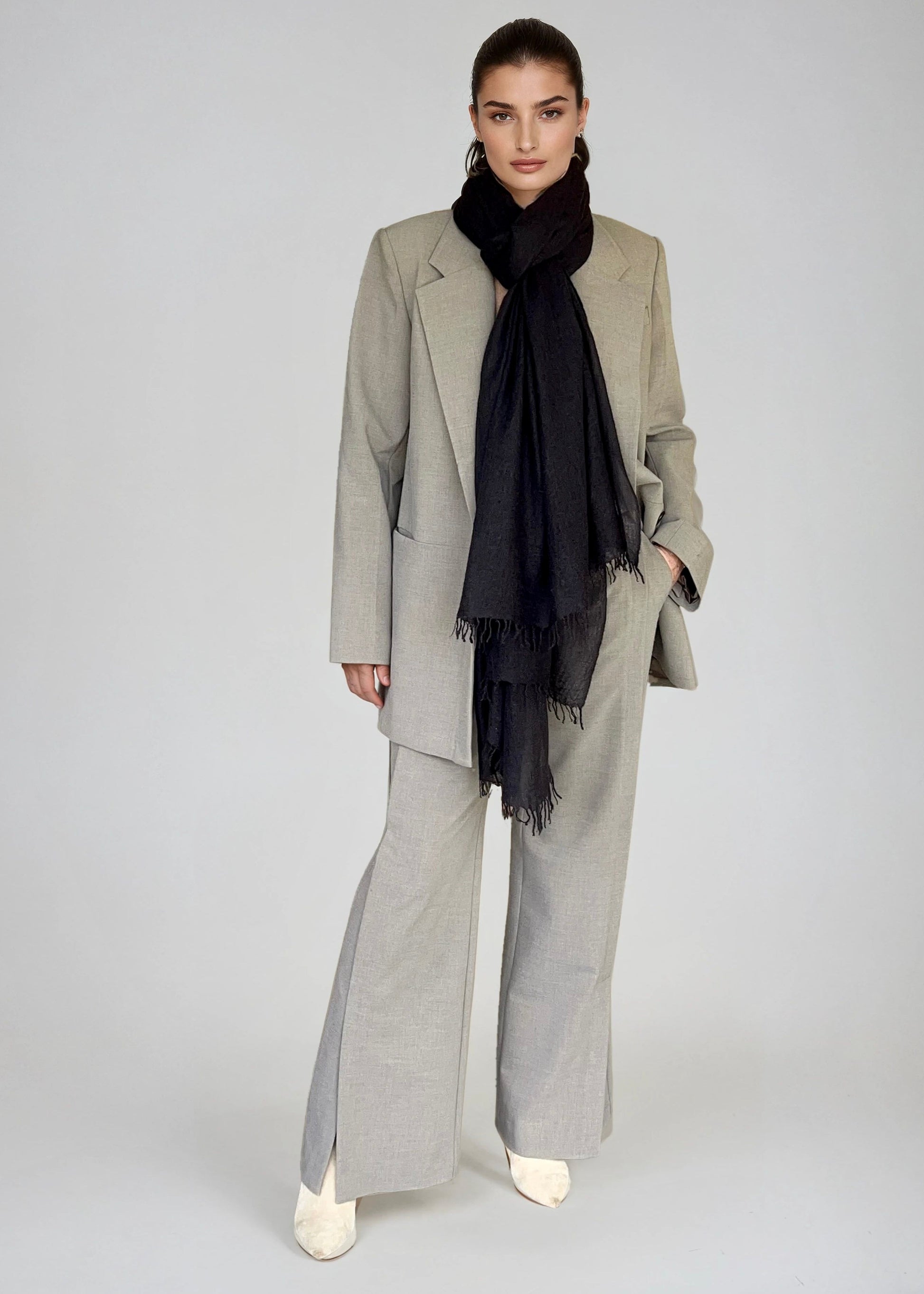 Person wearing a gray suit with a black scarf on a white background