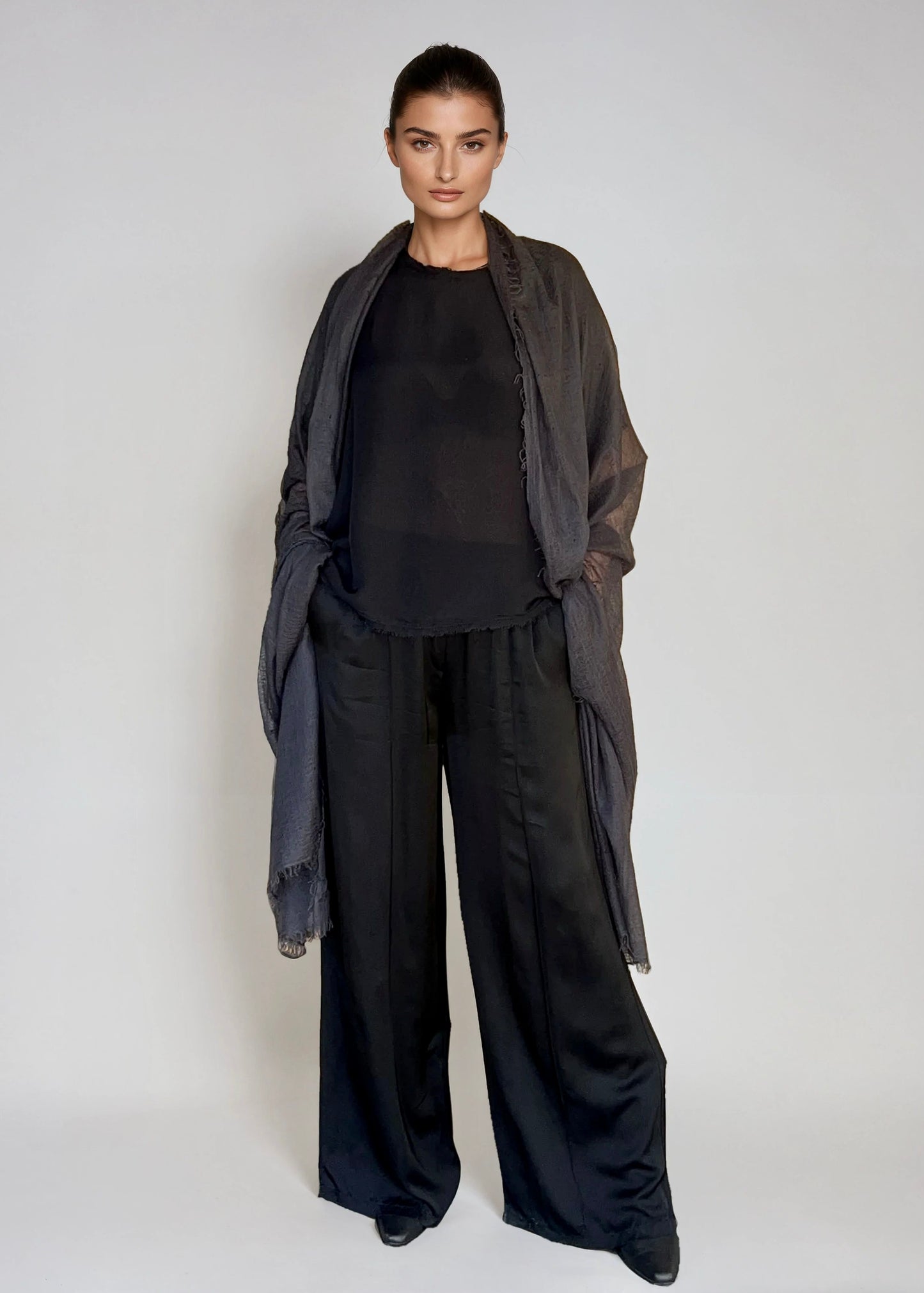 Woman wearing a black outfit with a lextra large charcoal cashmere shawl on a white background