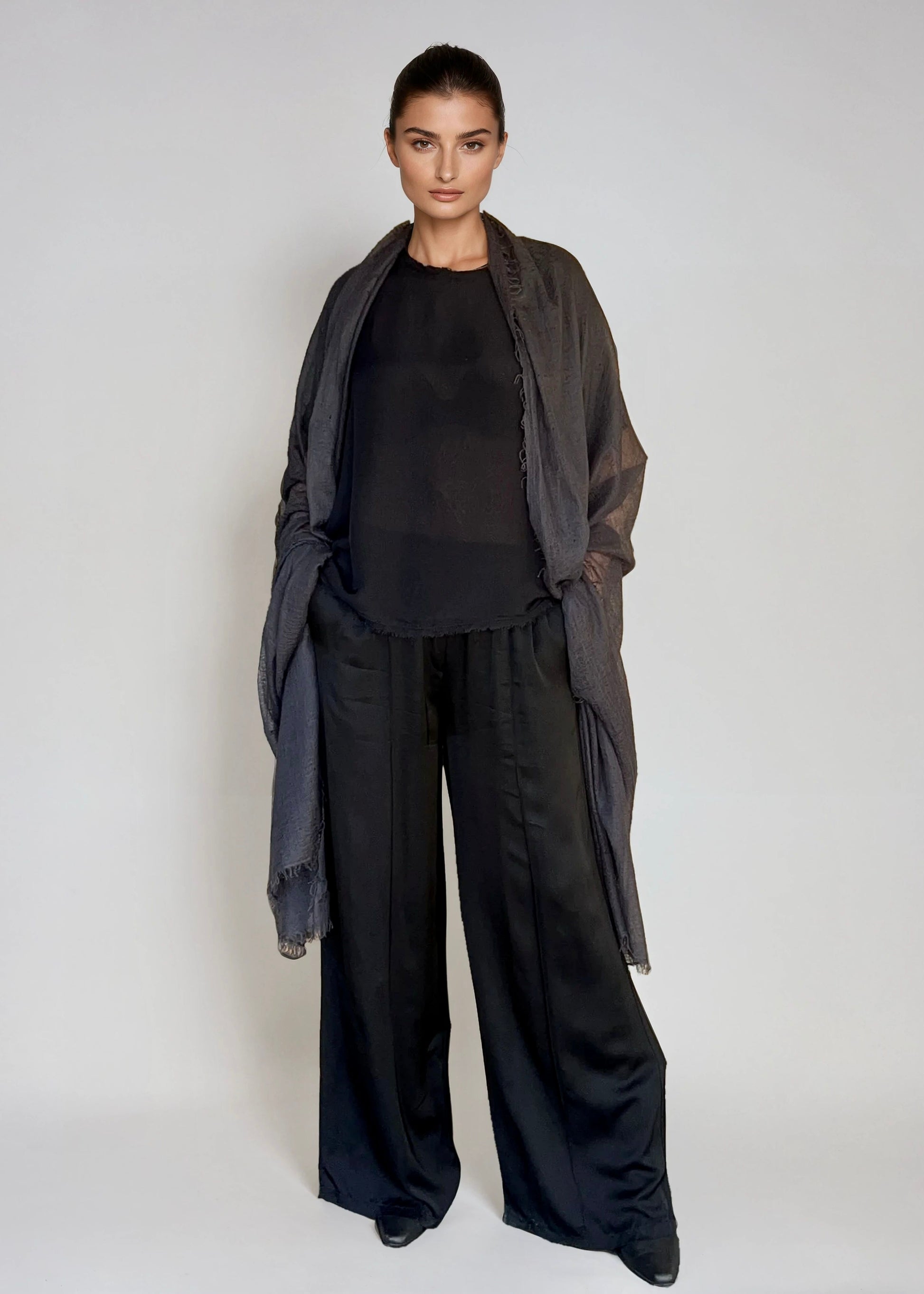 Woman wearing a black outfit with a lextra large charcoal cashmere shawl on a white background