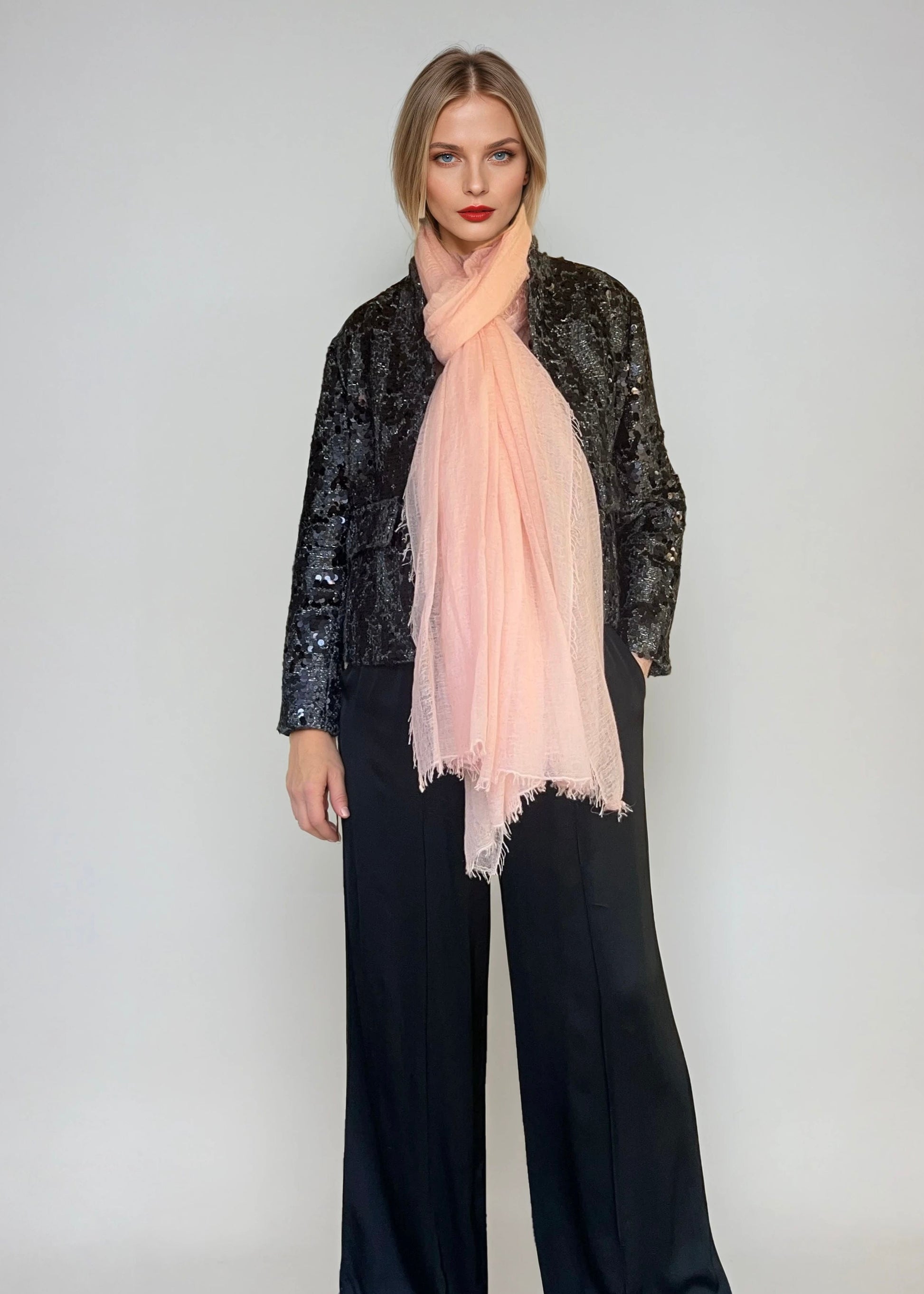 Woman wearing a extra large, light pink cashmere scarf in a studio.