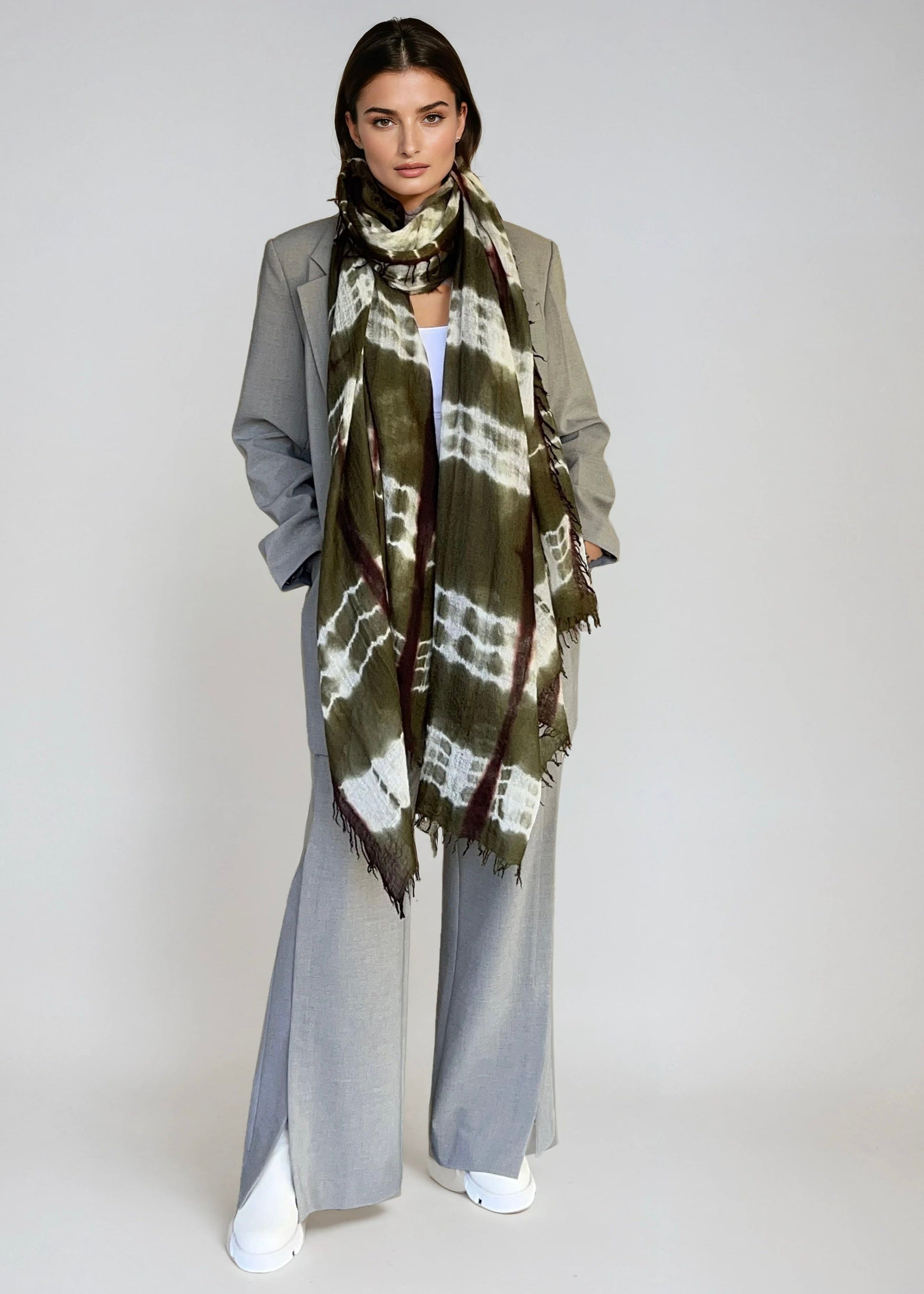 Woman wearing a green and brown patterned scarf on a white background