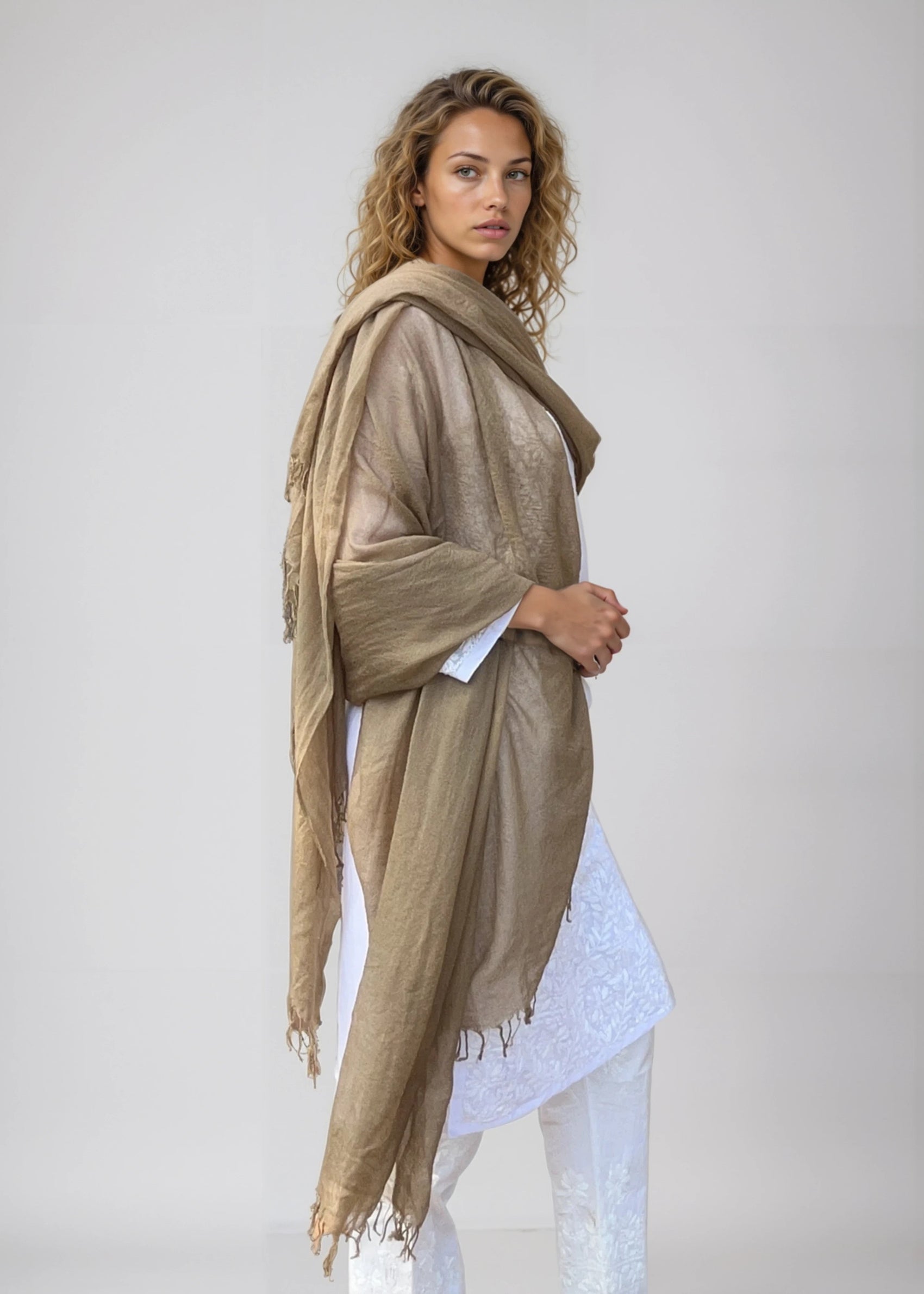 Woman wearing a beige scarf against a plain background