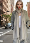 Woman standing on a city street wearing a suit and  soft grey extra large cashmere scarf