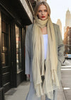 Woman wearing a beige extra large cashmere lightweight scarf on a city street