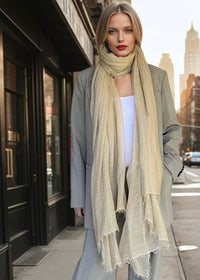 Woman wearing a beige extra large cashmere lightweight scarf on a city street