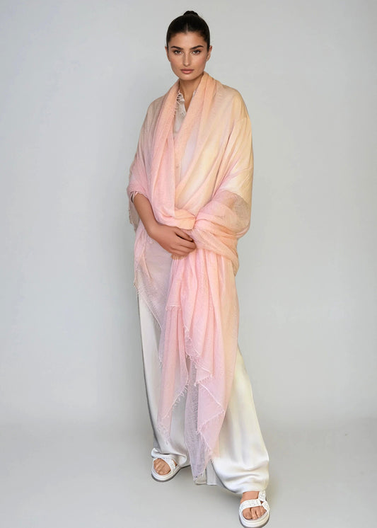 Woman wearing a extra large, light pink cashmere shawl in a studio.