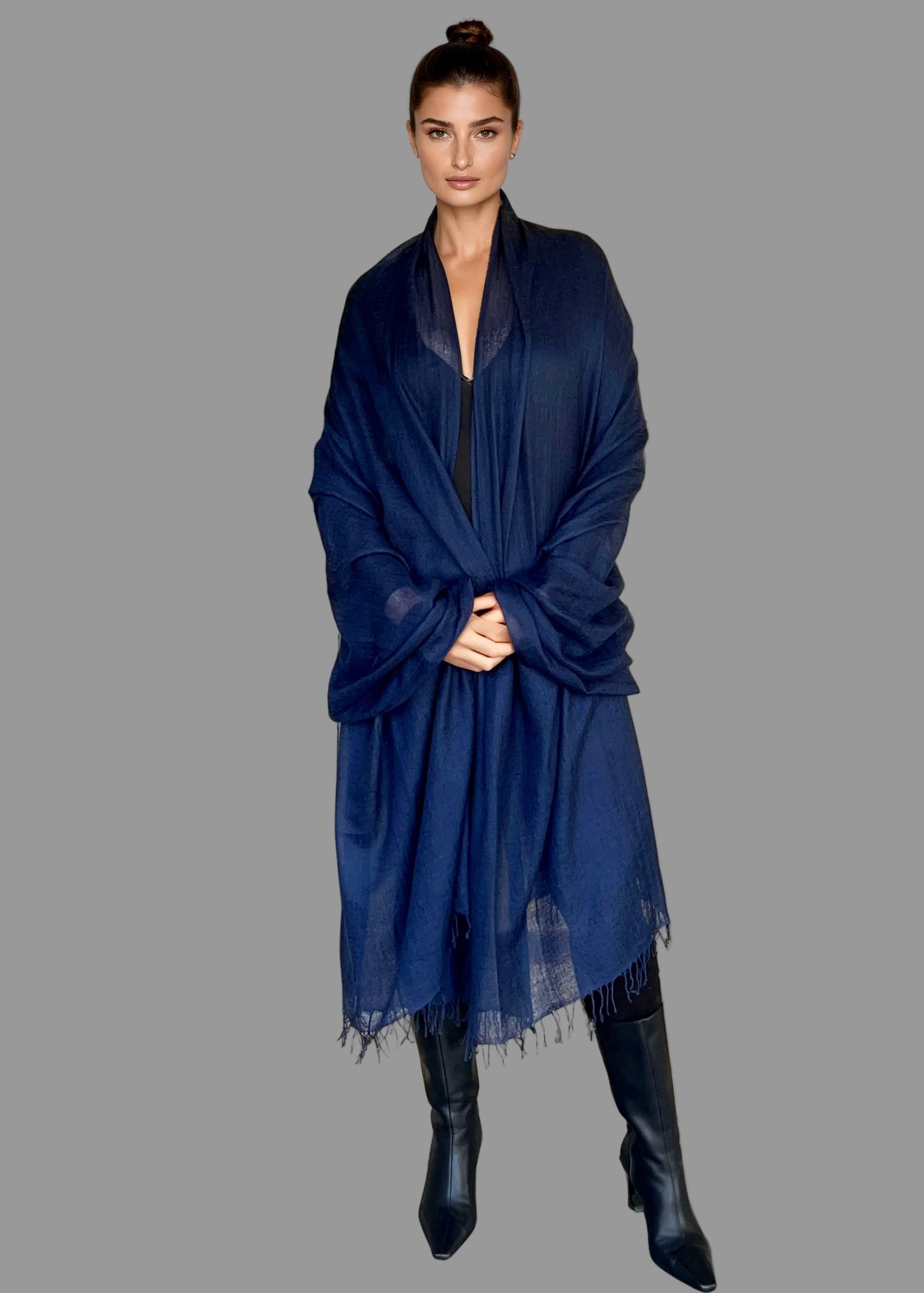 Woman wearing a blue scarf and black boots on a plain background