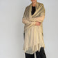Woman wearing a beige extra large cashmere shawl on a plain background