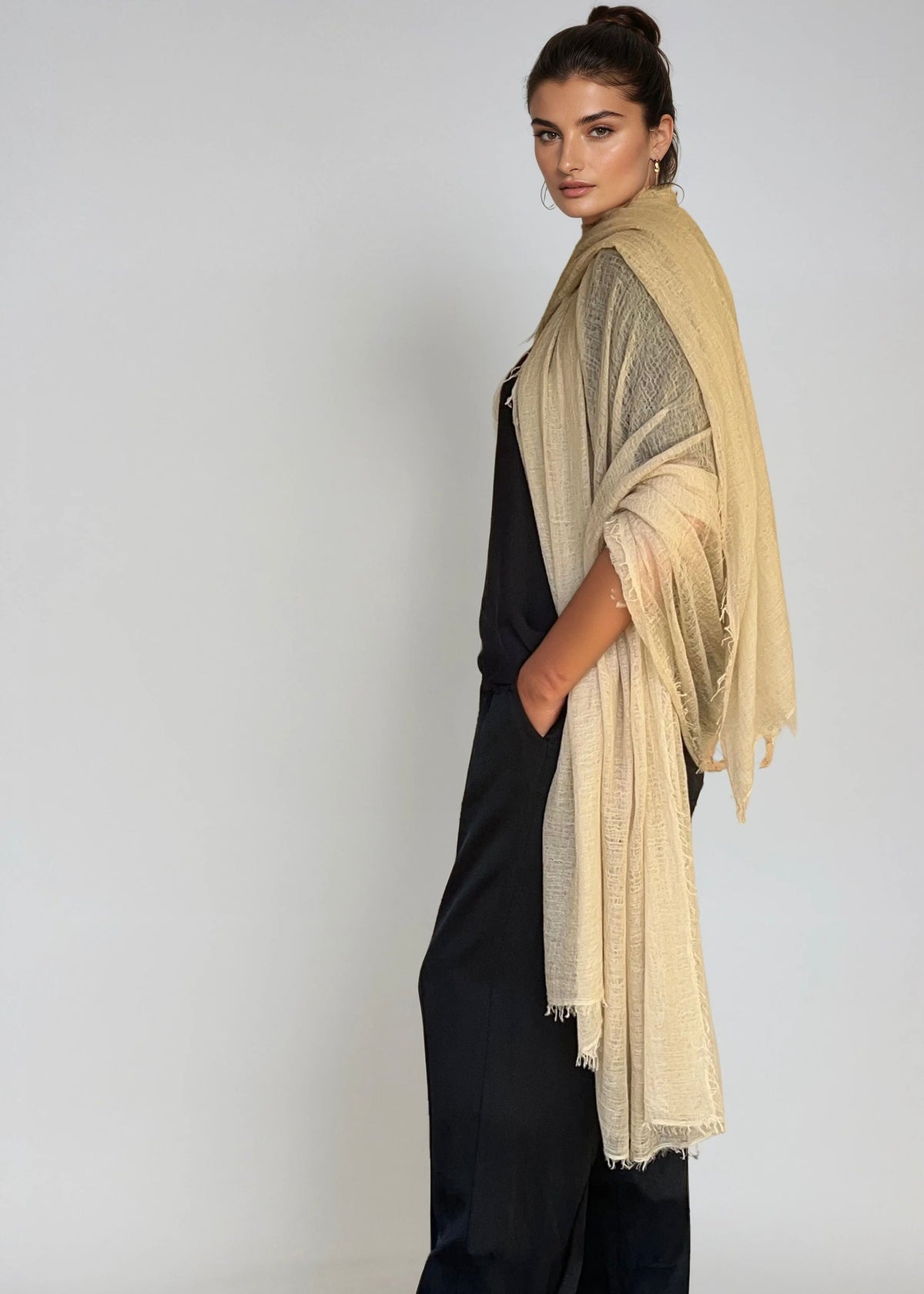 Woman wearing a beige extra large cashmere shawl on a plain background