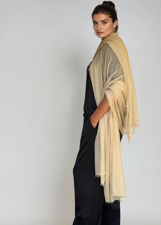 Woman wearing a beige extra large cashmere shawl on a plain background