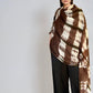 Woman wearing a cashmere extra large wrap in brown and white patterned on a plain background