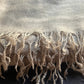 Close-up of a beige scarf with frayed edges on a dark surface