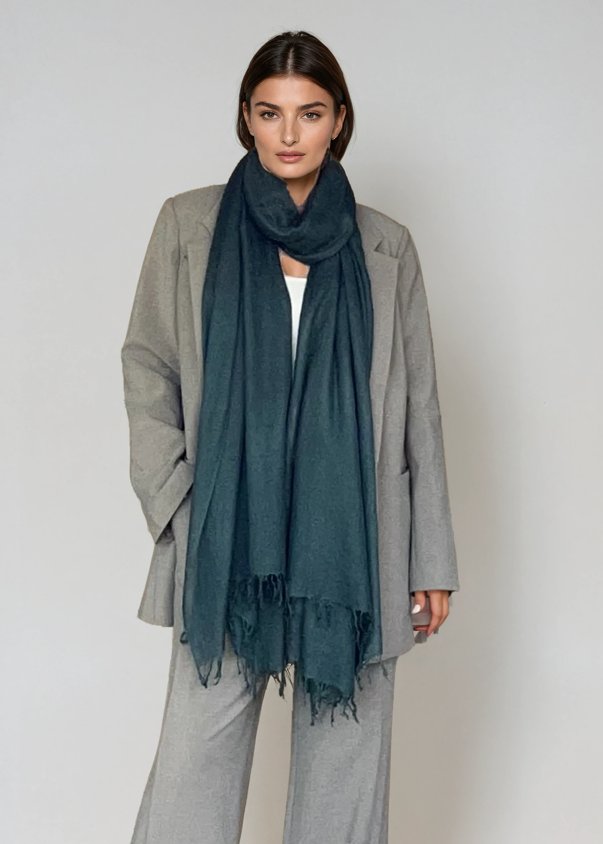 Person wearing a gray outfit with a dark green scarf on a white background