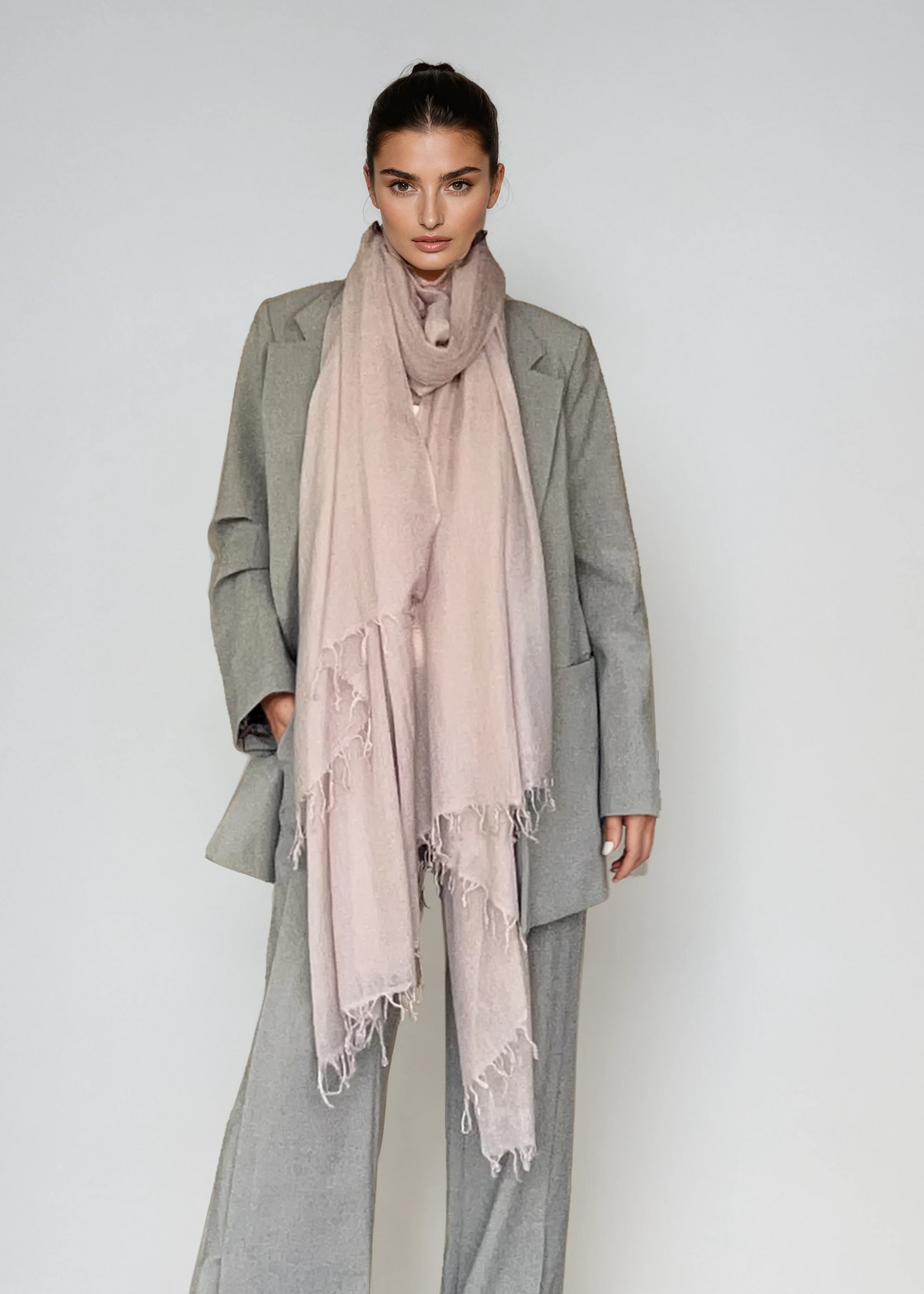 Person wearing a gray coat and pants with a pink scarf on a white background