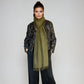 Woman wearing a green scarf and black patterned jacket on a white background
