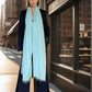 Woman wearing a extra large, cashmere opal blue shawl on a city street.