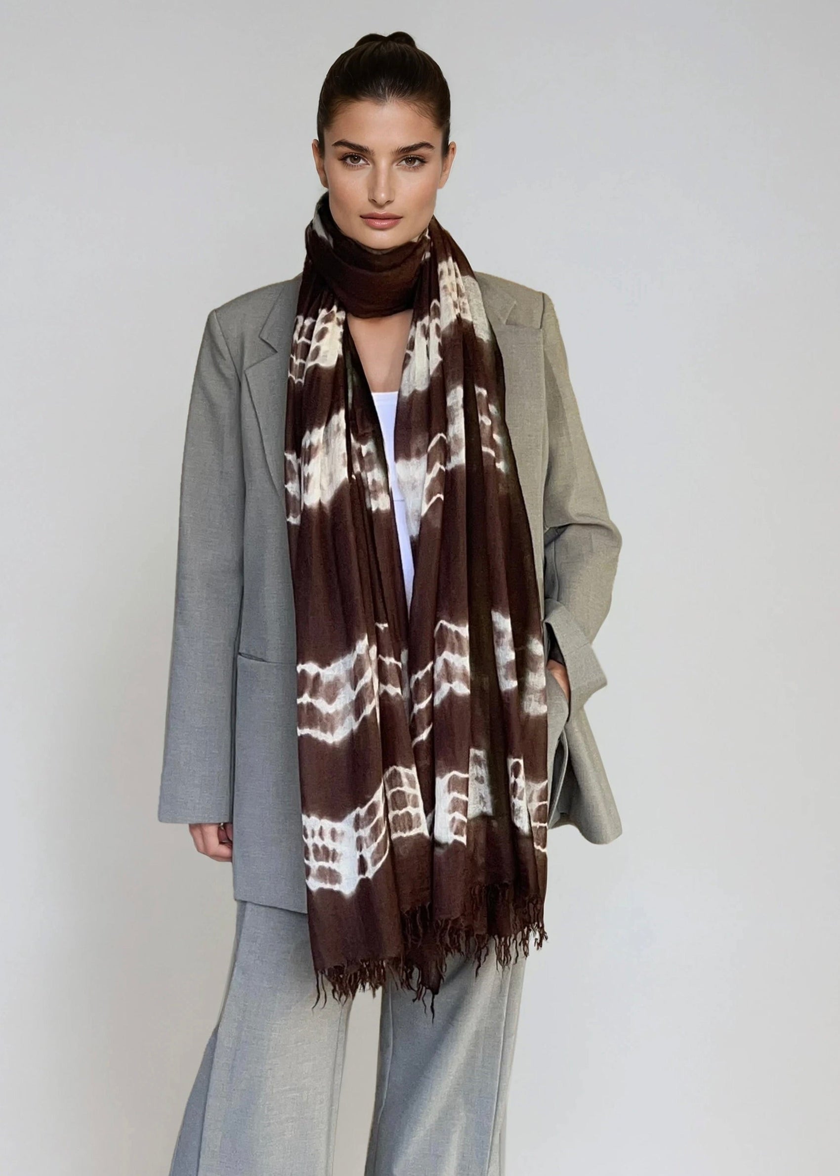 Woman wearing a gray coat and scarf with a white background