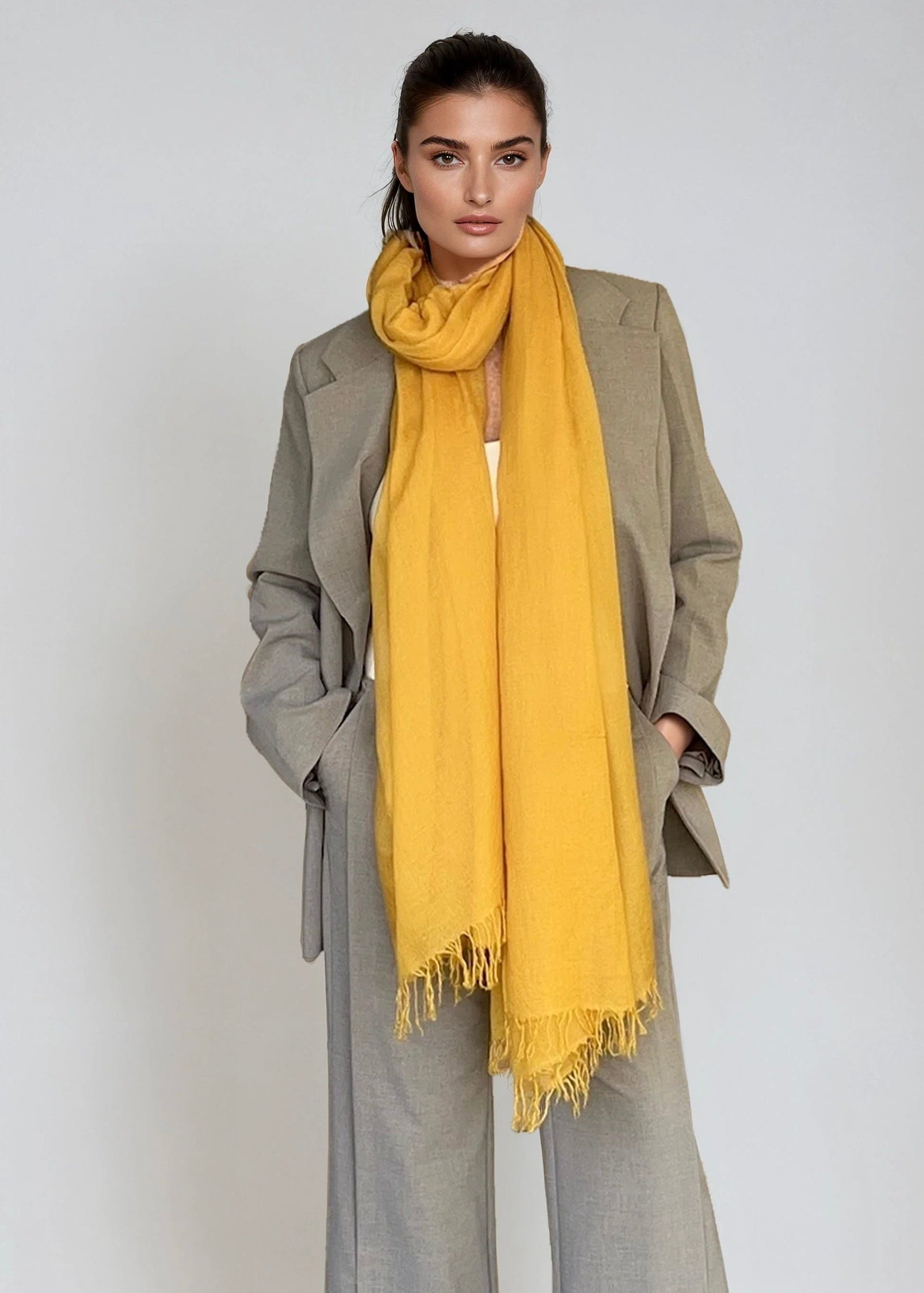 Woman wearing a yellow scarf and gray outfit on a white background
