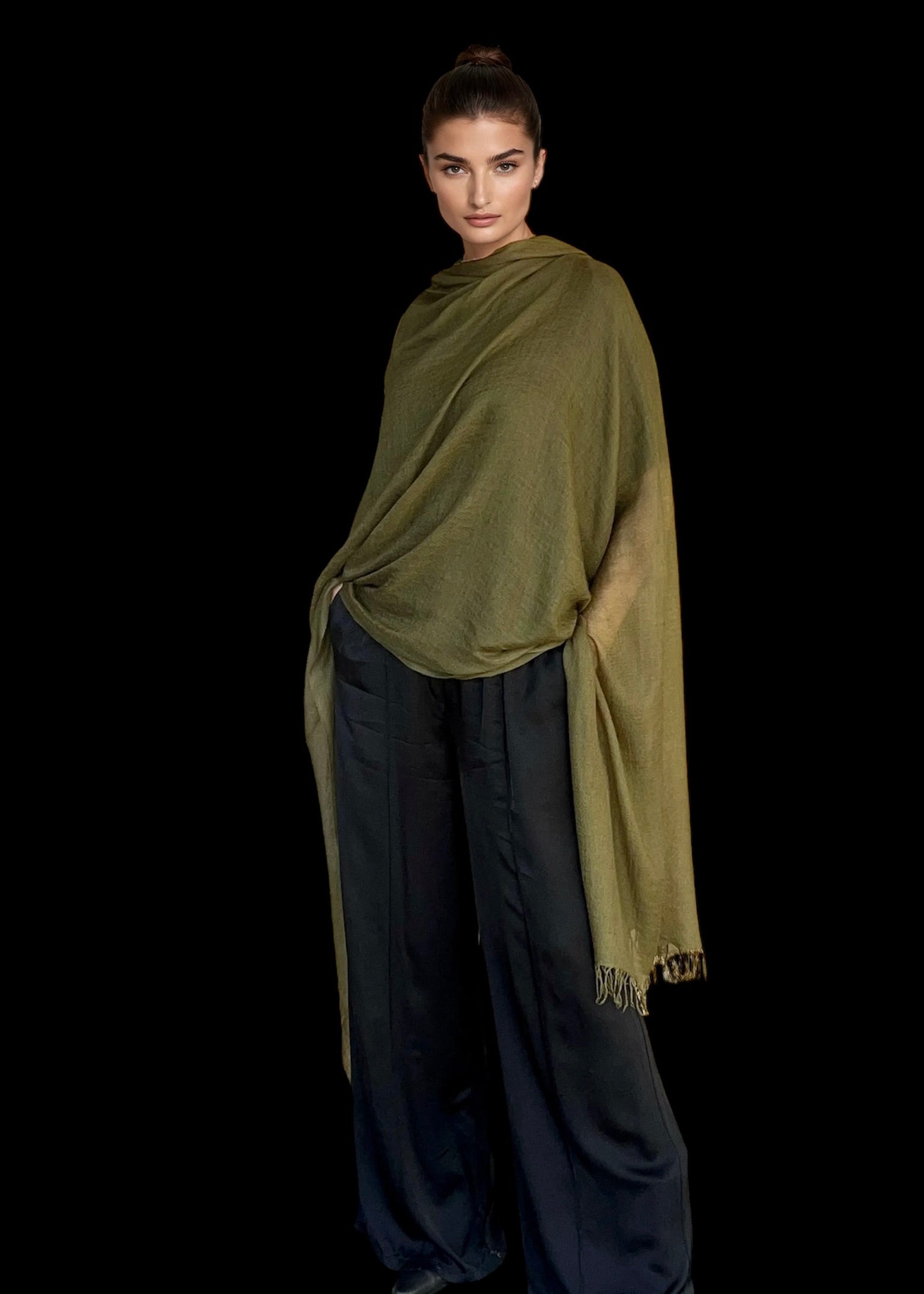 Woman wearing a green shawl over a dark outfit on a black background