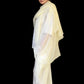 Woman wearing a light-colored outfit with a sheer overlay against a black background