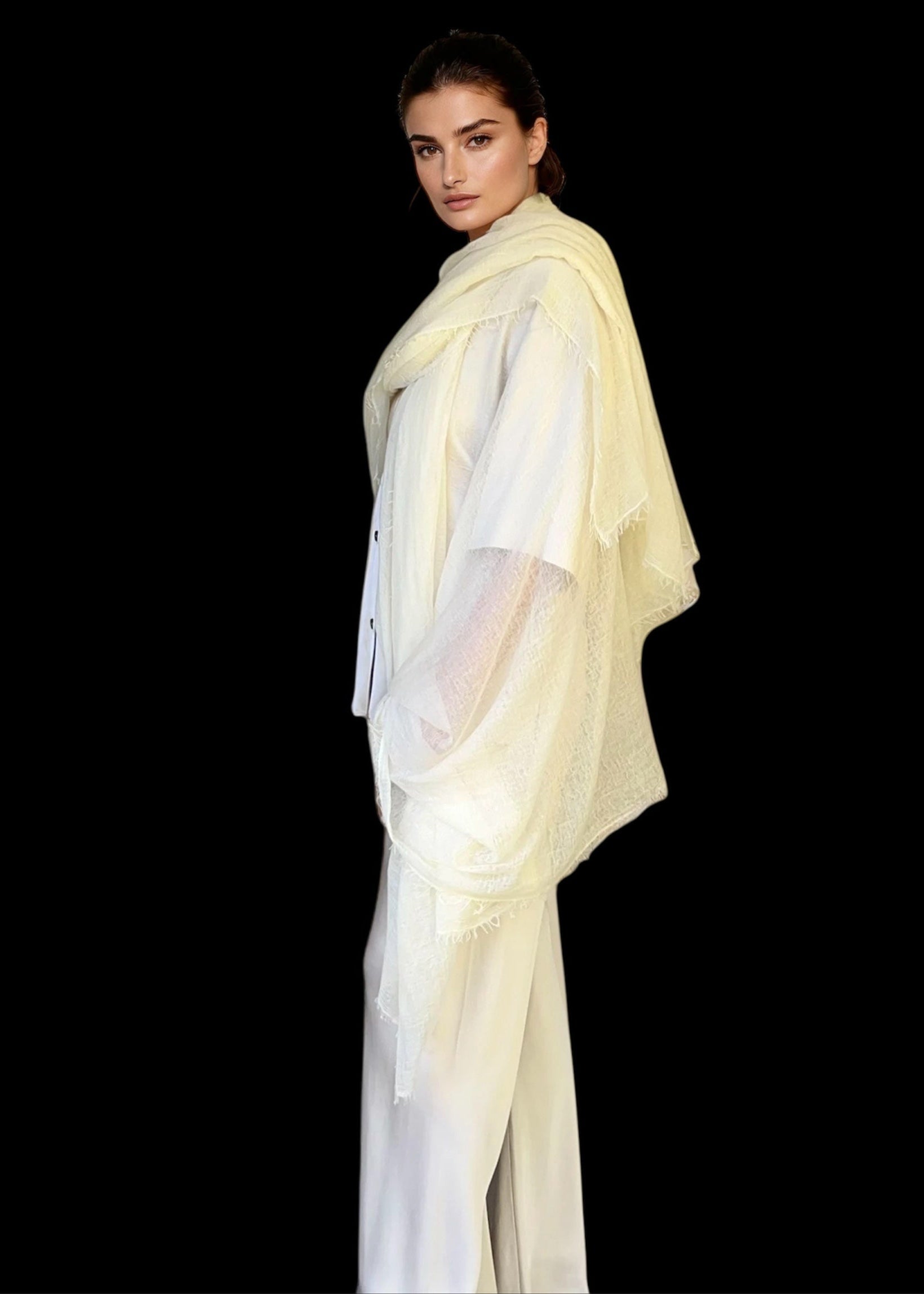 Woman wearing a light-colored outfit with a sheer overlay against a black background