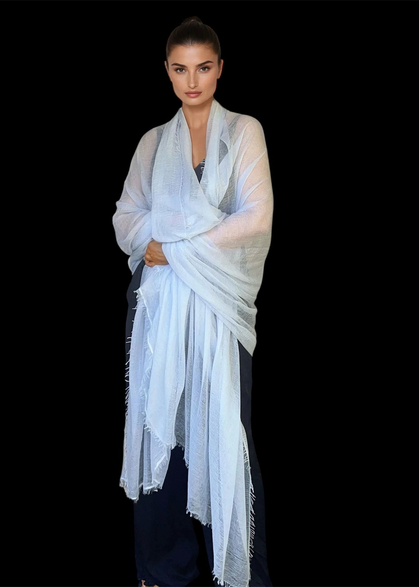 Woman wearing a light blue scarf against a black background
