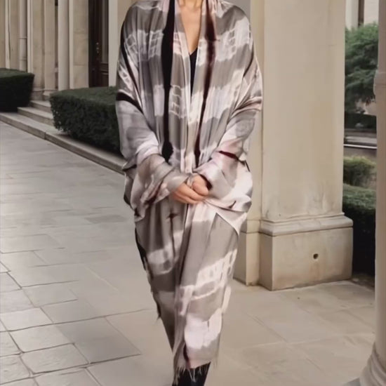 Video "Woman wearing limited edition hand tie-dyed extra large cashmere wrap in soft pink, taupe and brown showing unique color patterns"